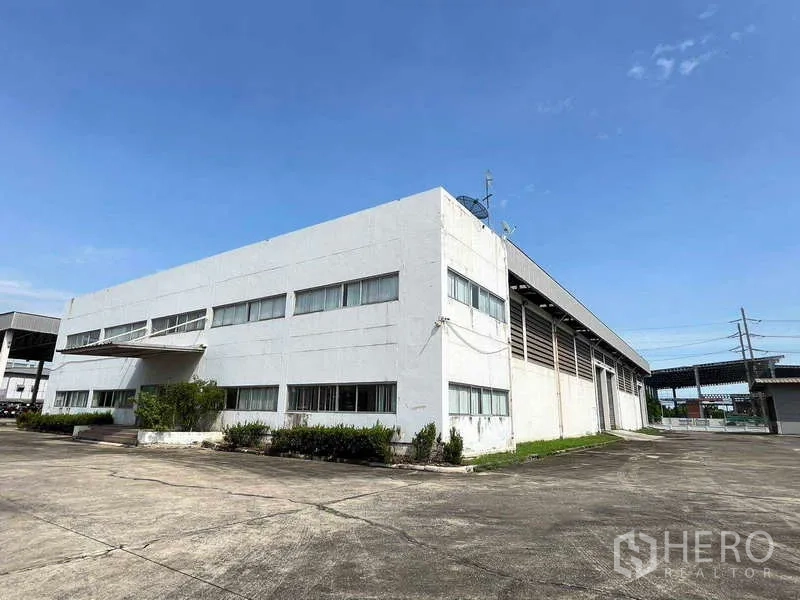 货栈 出租在Lat Krabang, Bangkok - 两层带办公区的仓库外观，宽阔车场与清澈蓝天，位于拉差空工业区。