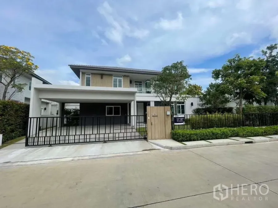Detached House for rent or sale in Bang Bua Thong, Nonthaburi - Front elevation with double carport canopy, black metal gate, and neat landscaping.