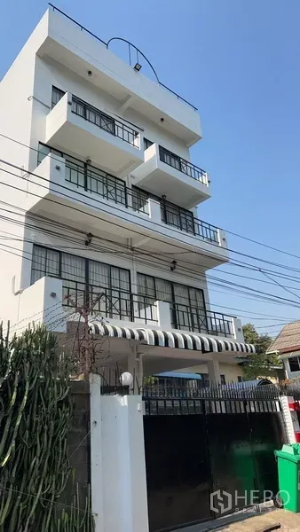 带办公室的家 出租或出售在Phra Khanong, Bangkok - 街景视角的现代住宅办公楼，带条纹雨棚、阳台和大门。