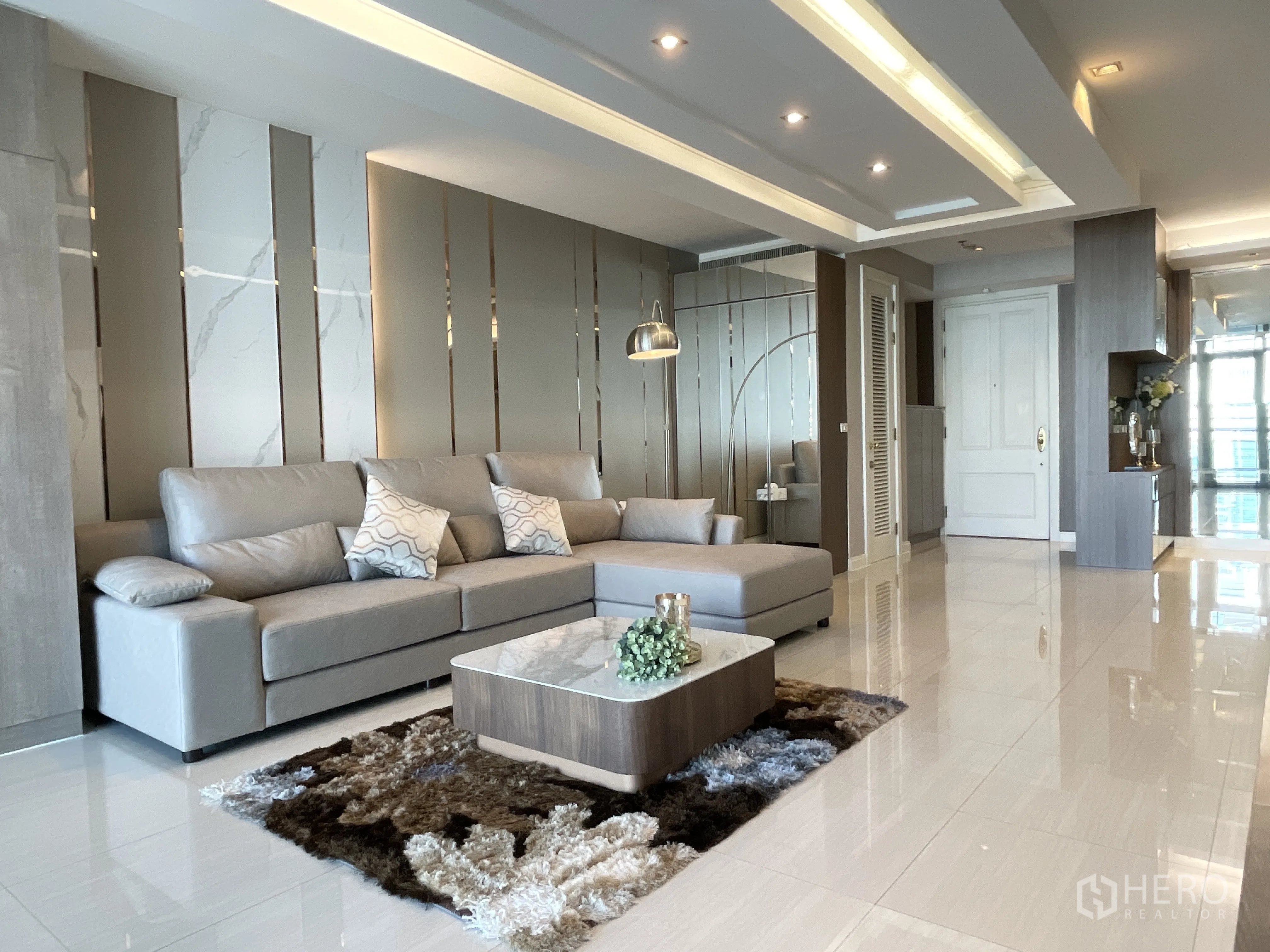 คอนโด for rent in Pathum Wan, Bangkok - โซนนั่งเล่นหรู โซฟาสีเทา ผนังไฮไลต์ และไฟดาวน์ไลท์