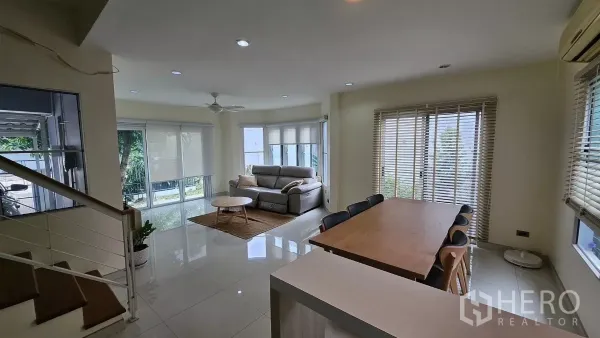 独立式住宅 出租在Khlong Toei, Bangkok - 宽敞客厅带转角窗与吊扇，旁为餐桌与嵌入式筒灯。