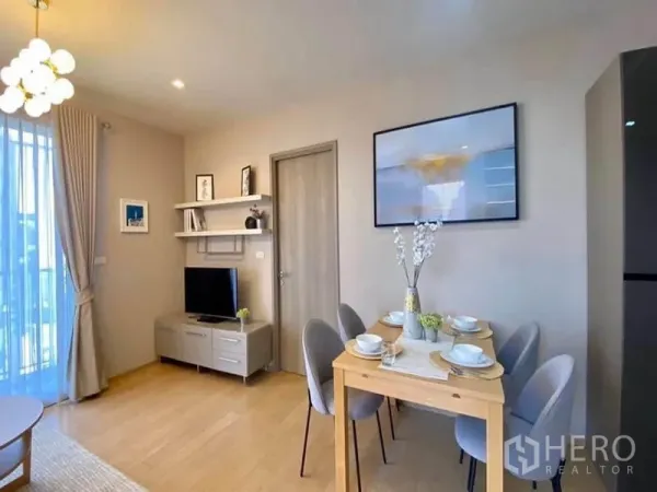 Condominium for rent or sale in Khlong Toei, Bangkok - Dining table set for four beside TV console and shelving in a neutral-tone living area.