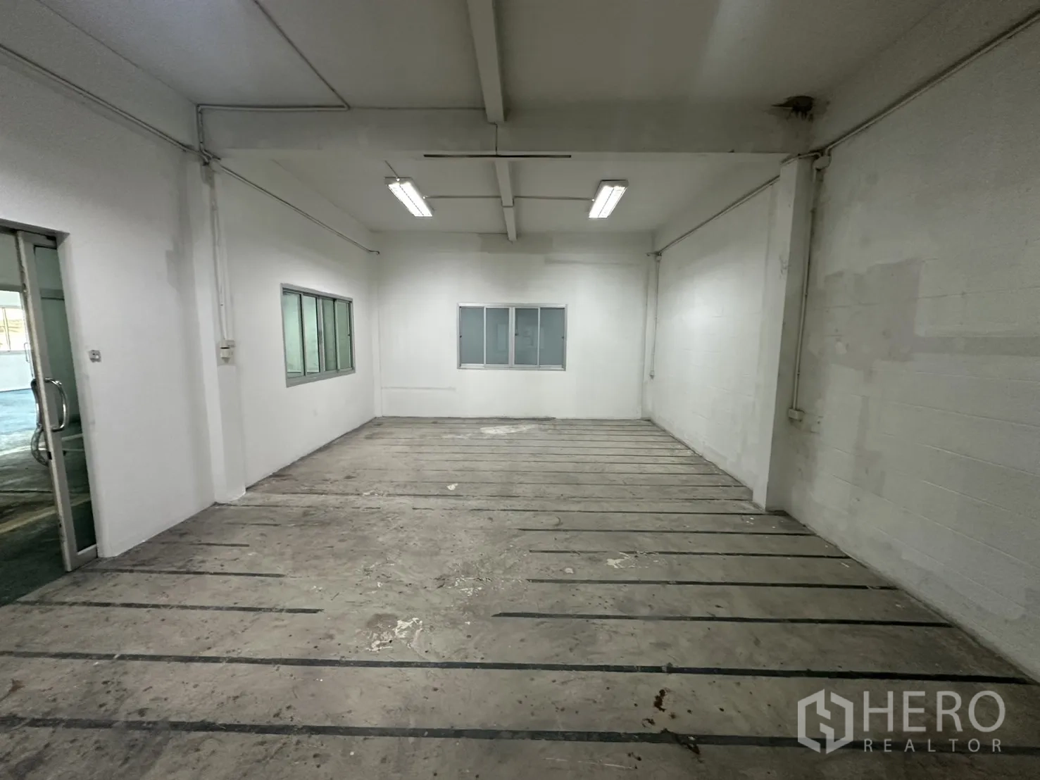 Warehouse for rent in Bang Na, Bangkok - Bright workroom with windows and marked concrete flooring.