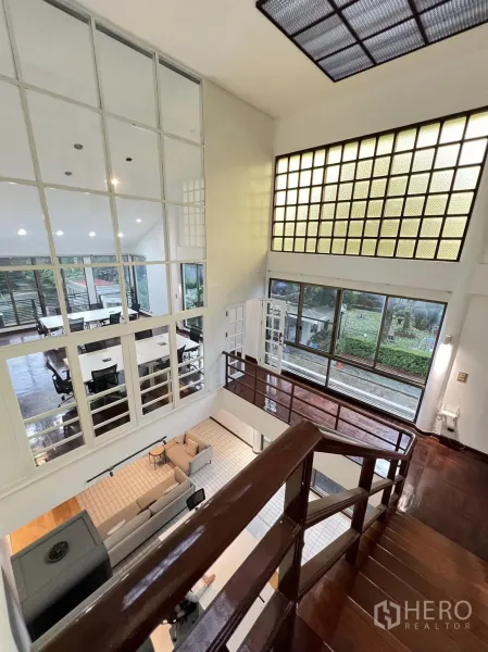 ทาวน์เฮาส์ ให้เช่าในWatthana, Bangkok - โถงรับแขกเพดานสูงพร้อมชั้นลอย ผนังกระจกบล็อก และบันไดไม้เงา