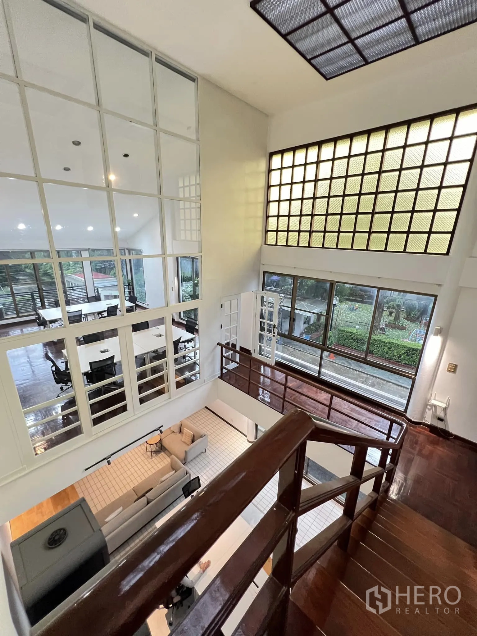 ทาวน์เฮาส์ ให้เช่าในWatthana, Bangkok - โถงรับแขกเพดานสูงพร้อมชั้นลอย ผนังกระจกบล็อก และบันไดไม้เงา