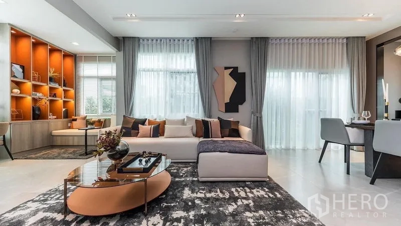 Detached House for rent in Prawet, Bangkok - Living area facing display shelves and full-height windows with sheer drapes.