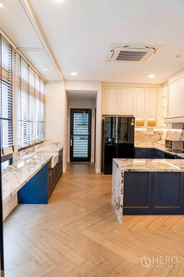 Detached House for rent in Saphan Sung, Bangkok - Gourmet kitchen with marble countertops, island and navy cabinetry on herringbone floor.