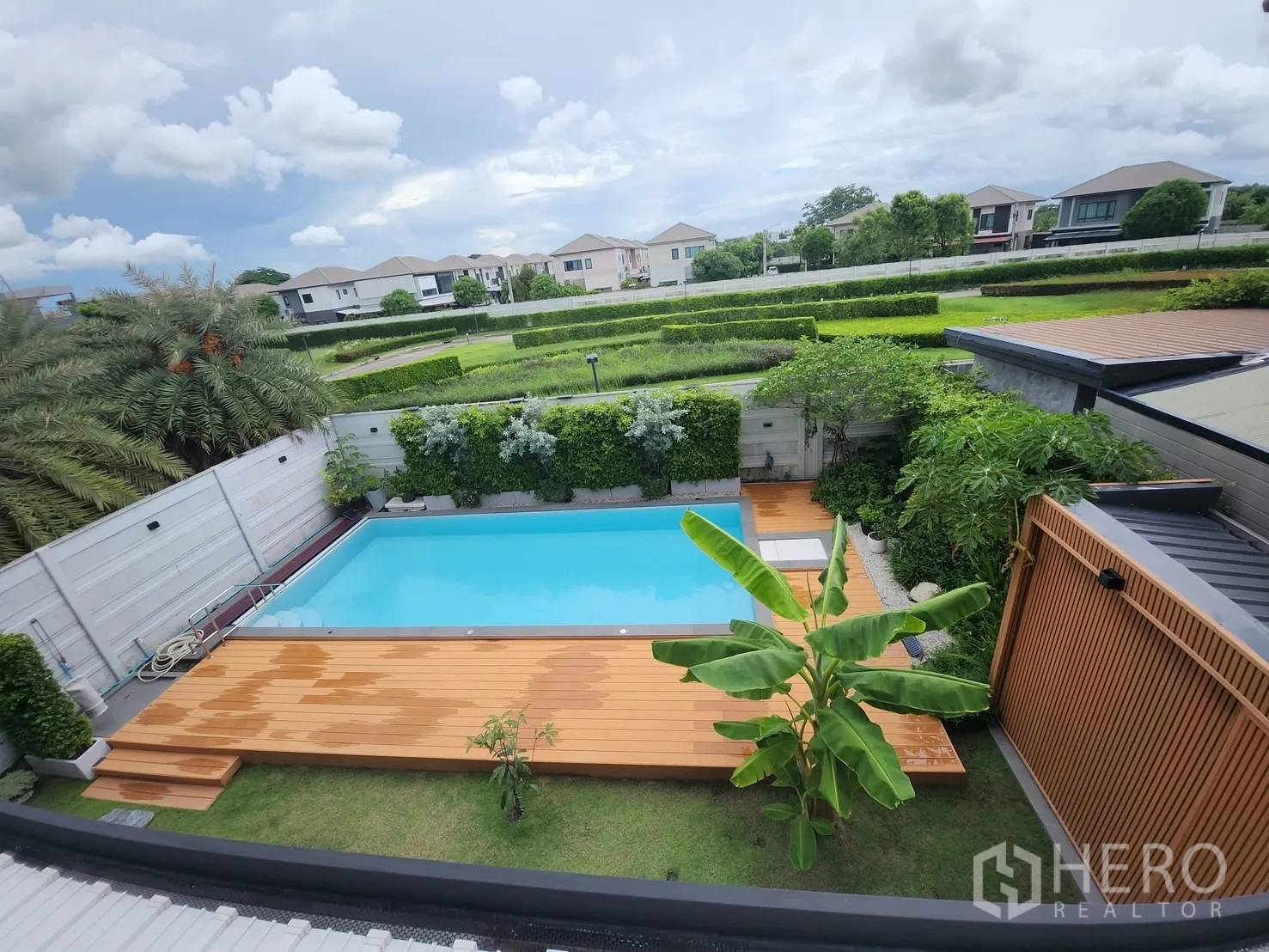 Detached House for rent in Bang Phli, Samut Prakan - Aerial view of the pool, timber deck and tall privacy hedges with the neighborhood in the background.