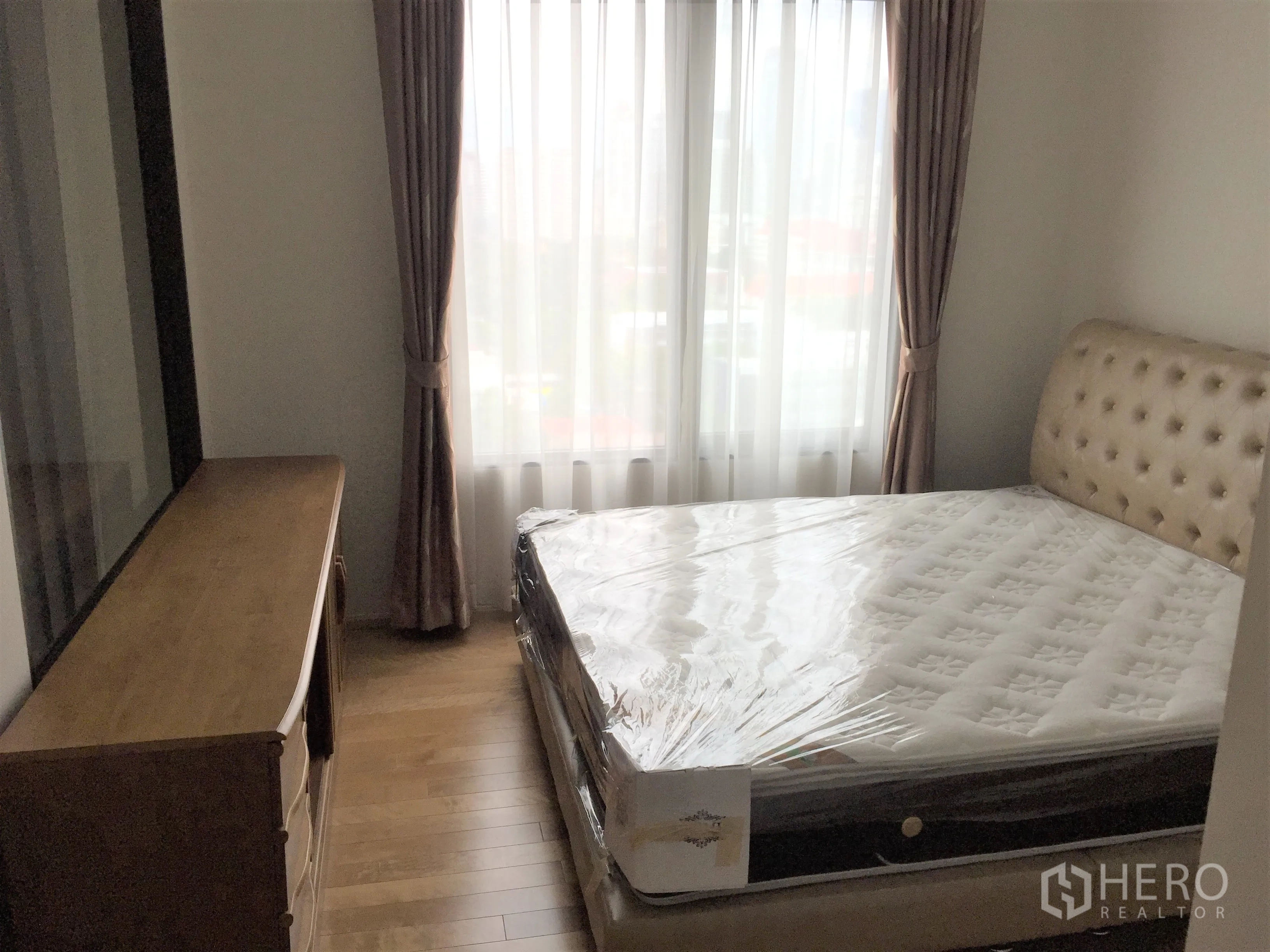 คอนโด ให้เช่าในRatchathewi, Bangkok - ห้องนอนอบอุ่น เตียงหุ้มบุ หน้าต่างบานใหญ่ พื้นไม้ และตู้ลิ้นชัก ในคอนโดราชเทวี