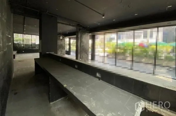 零售空间 出租在Khlong Toei, Bangkok - 深色毛坯商铺，沿窗长吧台与落地玻璃。