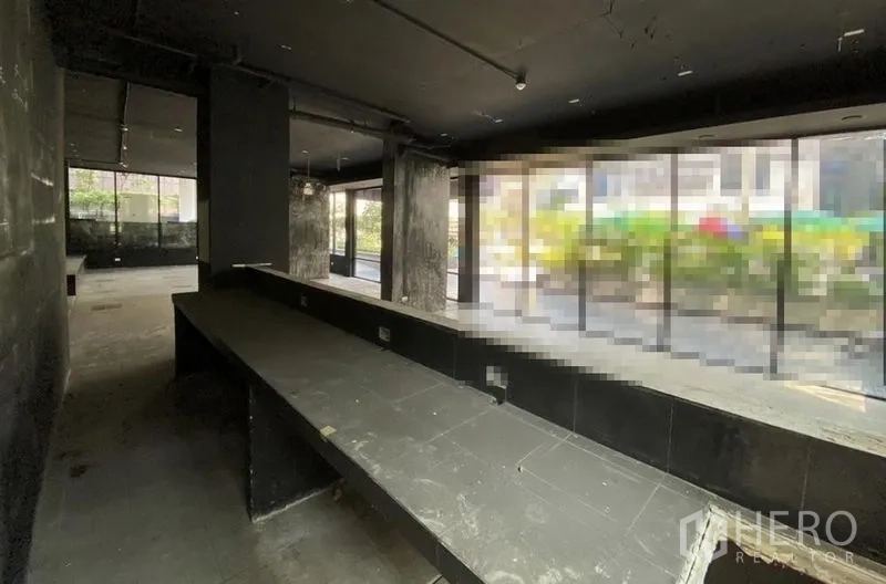 零售空间 出租在Khlong Toei, Bangkok - 深色毛坯商铺，沿窗长吧台与落地玻璃。