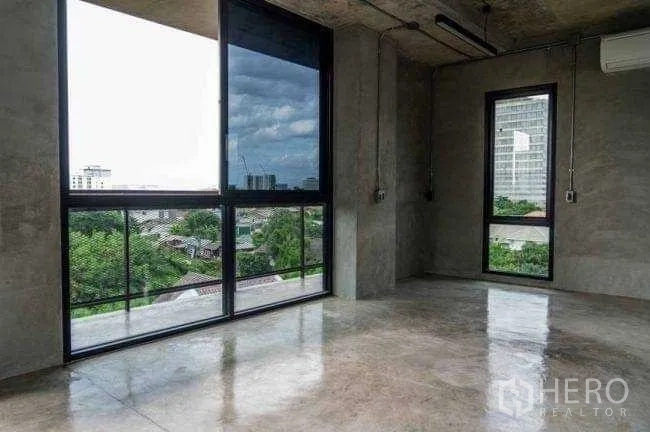 Office Space for rent or sale in Lak Si, Bangkok - Corner office with polished concrete floors and dual windows framing skyline views.
