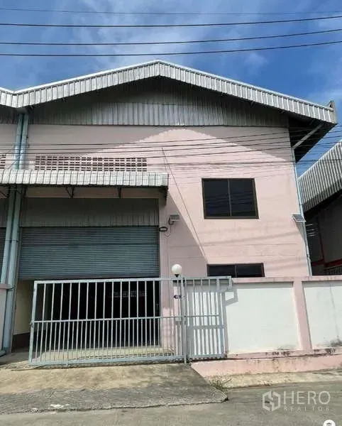 Warehouse for rent in Bang Bua Thong, Nonthaburi - Front view of the warehouse facade showing metal roof, security gate and roller shutter door.