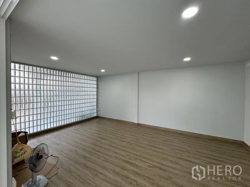 Townhouse for sale in Bueng Kum, Bangkok - Large multipurpose room with wood-look flooring and a full glass block feature wall.