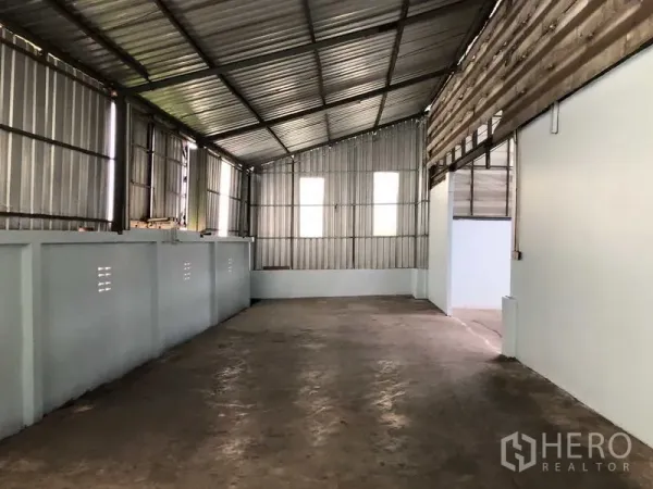 Warehouse for rent in Sai Noi, Nonthaburi - Partitioned side storage area with metal sheet walls and concrete floor.