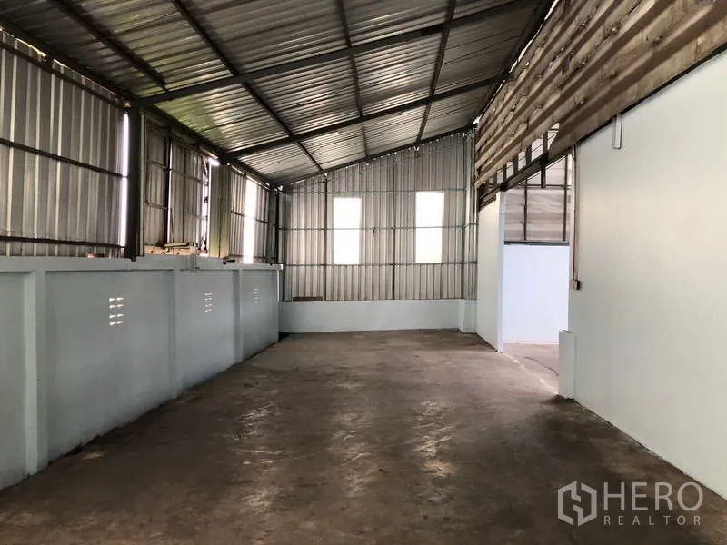 Warehouse for rent in Sai Noi, Nonthaburi - Partitioned side storage area with metal sheet walls and concrete floor.