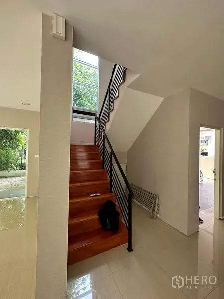 独立式住宅 出售在Prawet, Bangkok - 木阶黑色扶手的楼梯，旁有通高采光窗。
