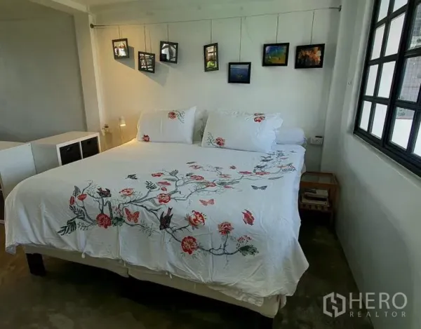 ทาวน์เฮาส์ ให้เช่าในKhlong Toei, Bangkok - ห้องนอนสว่างเตียงคิงไซส์ ชุดเครื่องนอนลายดอกไม้ และกรอบรูปแขวนใกล้หน้าต่างมุม