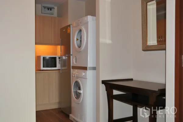 公寓 出租在Khlong Toei, Bangkok - 紧凑厨房，冰箱、微波炉与叠放式洗烘设备。