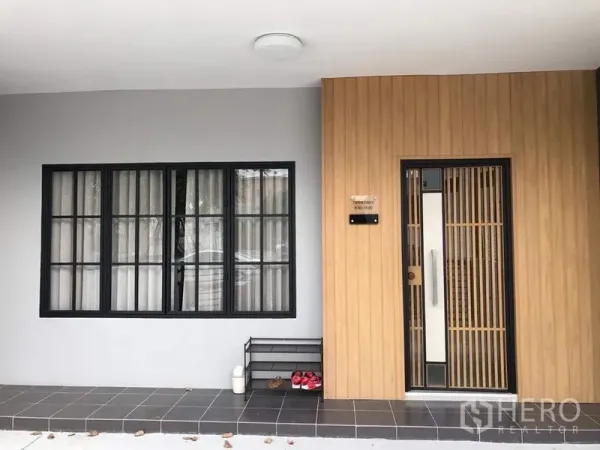 Townhouse for rent - Modern townhouse entrance with wood slat door, black-framed window, and tiled porch.