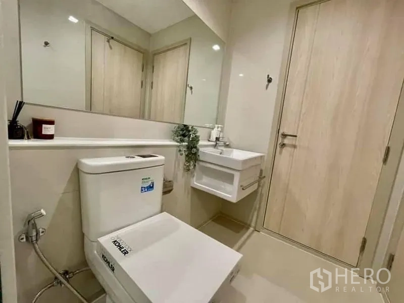 Condominium for rent in Pathum Wan, Bangkok - Compact second bathroom with floating sink, wide mirror and Kohler toilet.