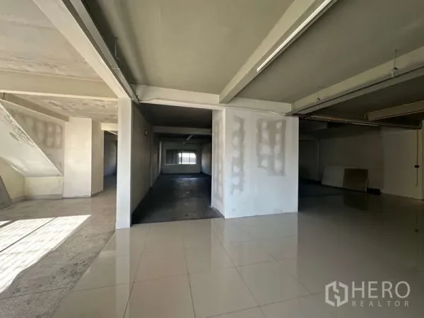 办公空间 出租在Phra Khanong, Bangkok - 宽敞办公室，前方为瓷砖接待区，过渡到原始工作区，吊顶灯具。