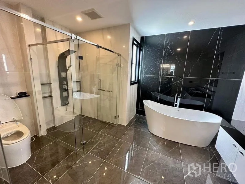 Detached House for sale - Luxurious bathroom with freestanding tub, glass shower and black marble feature wall.