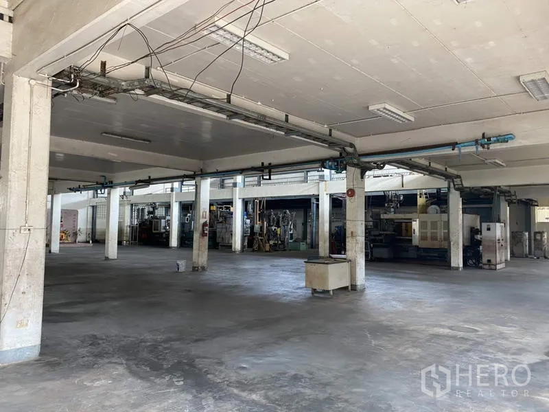 Factory for sale in Khlong Luang, Pathum Thani - Ground-level workshop space with concrete floor, columns and utility lines.