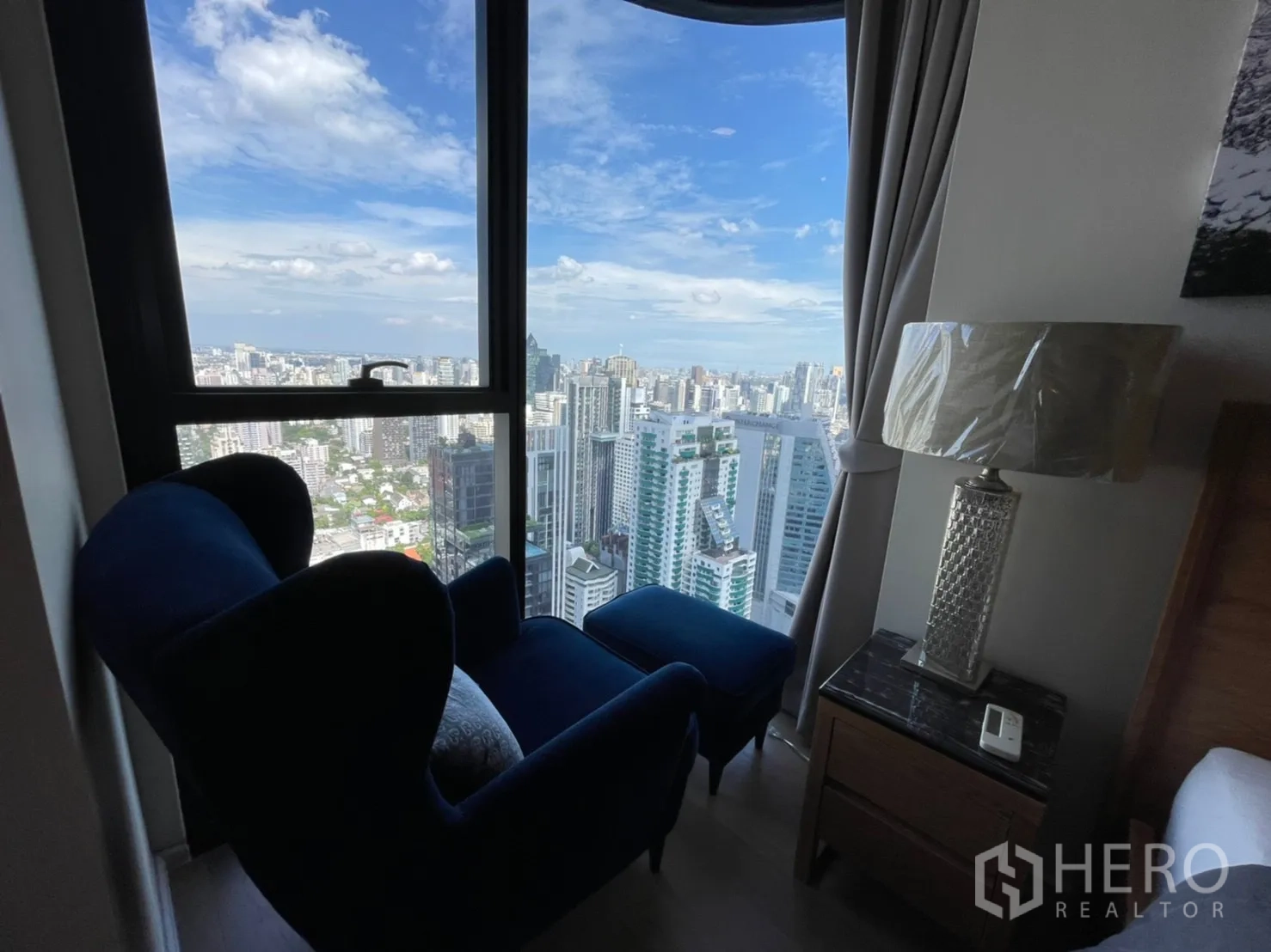 公寓 for rent in Watthana, Bangkok - 窗边蓝色躺椅，享受开阔的城市景观。