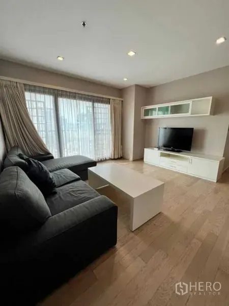 คอนโด ให้เช่าในKhlong Toei, Bangkok - ห้องนั่งเล่นสว่าง โซฟา L-Shape ตู้วางทีวี และหน้าต่างสูงจรดเพดาน