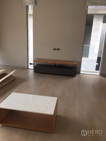 บ้าน ให้เช่าในWatthana, Bangkok - ห้องนั่งเล่นมินิมอล พื้นไม้สีอ่อน โต๊ะกลางเตี้ยและชั้นวาง พร้อมช่องแสงแนวตั้ง