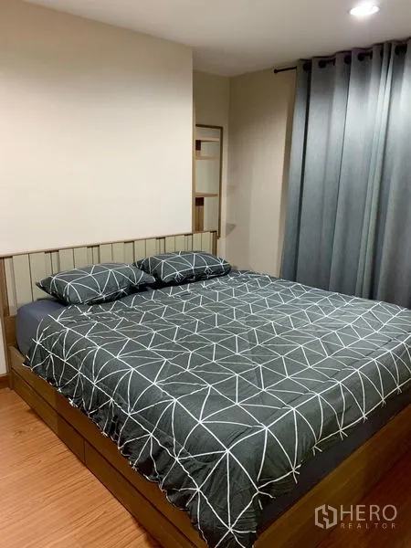 Condominium for rent in Huai Khwang, Bangkok - Bedroom with king bed, wooden base drawers and blackout curtains.