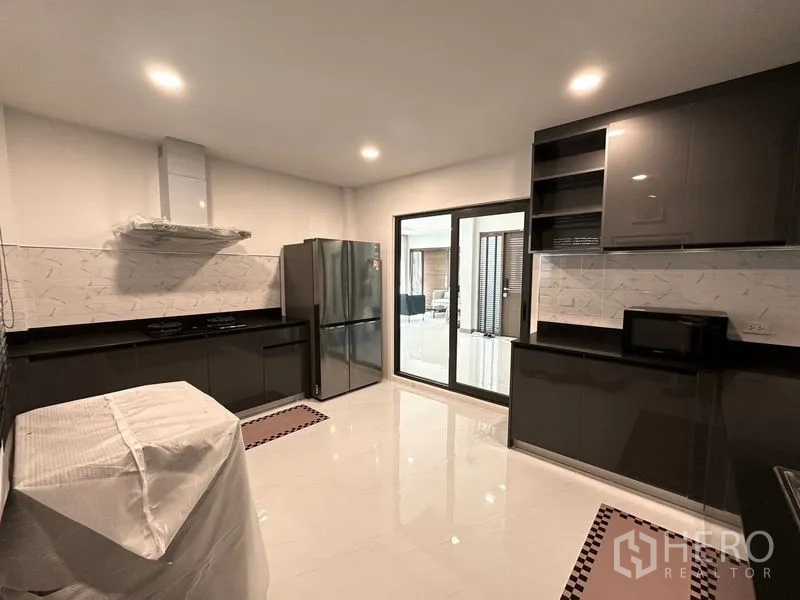Detached House for rent or sale in Bang Phli, Samut Prakan - Enclosed kitchen with glossy cabinets, fridge and sliding glass door.