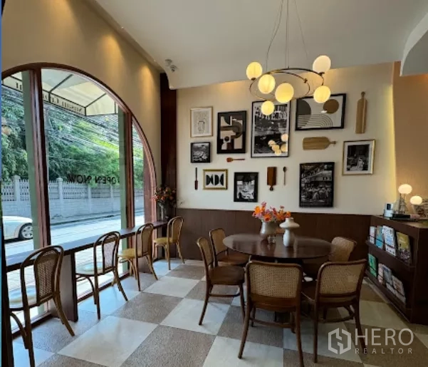 零售空间 出租在Watthana, Bangkok - 拱形落地窗旁的明亮座区，棋盘格地面与吊灯。