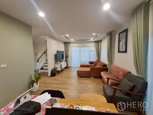 บ้าน ให้เช่าหรือขายในLam Luk Ka, Pathum Thani - ห้องนั่งเล่นโปร่งสบาย พื้นไม้ไฟดาวน์ไลท์ หน้าต่างบานใหญ่และโซฟา