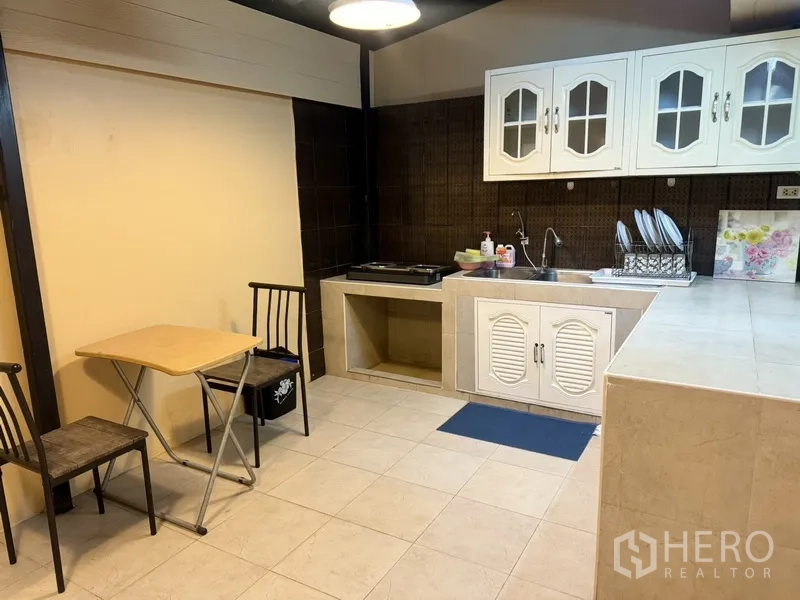 联排别墅 出租在Prawet, Bangkok - 厨房操作区，水槽、瓷砖台面与小型餐桌椅。