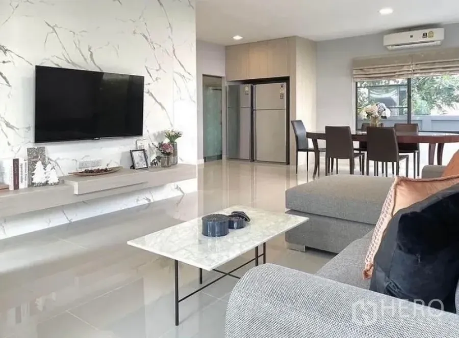 Detached House for rent in Prawet, Bangkok - Bright living and dining area with marble feature wall, mounted TV and L‑shaped sofa in a detached house in Prawet, Bangkok.