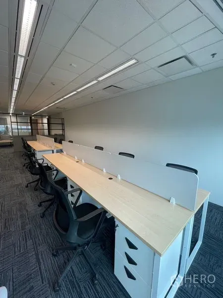 Office Space for rent in Dusit, Bangkok - Row of shared desks with partitions and storage drawers in a bright open-plan area.