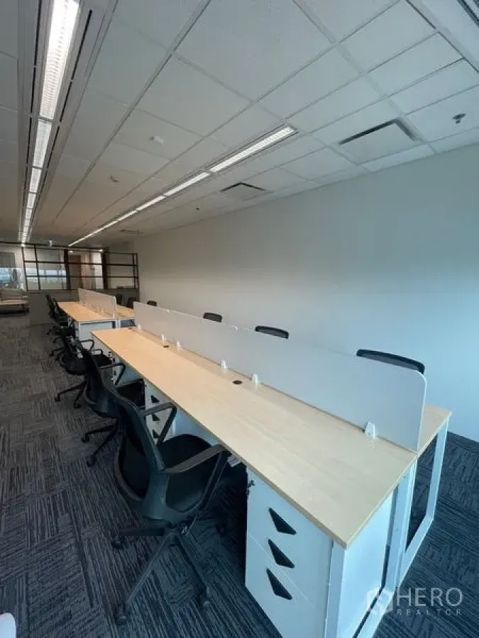 Office Space for rent in Dusit, Bangkok - Row of shared desks with partitions and storage drawers in a bright open-plan area.
