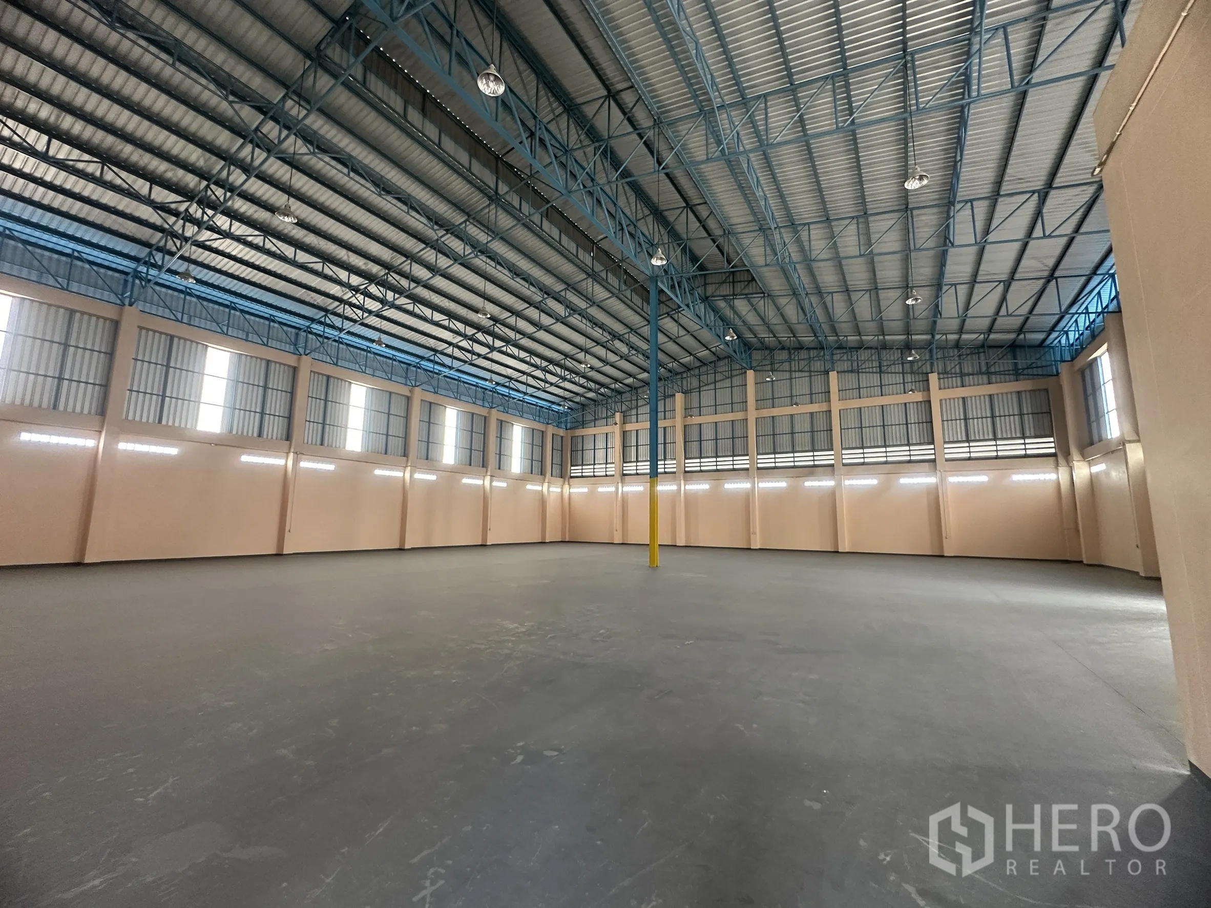 Warehouse for rent in Lat Lum Kaeo, Pathum Thani - Large clear-floor warehouse space under metal truss roof with lighting fixtures.