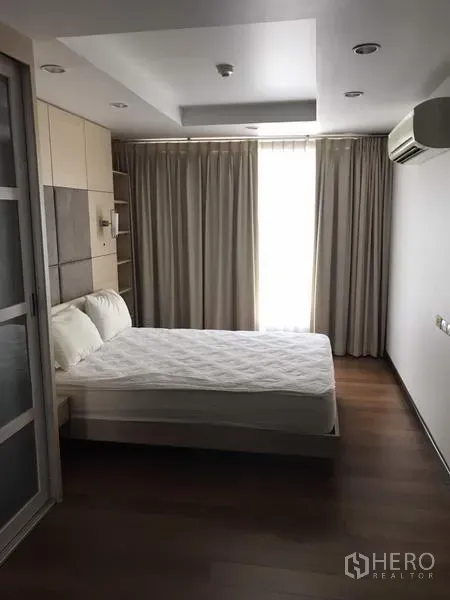 Condominium for rent in Watthana, Bangkok - Bedroom with queen bed, wood flooring, large window with blackout curtains, recessed lighting and sliding wardrobe.