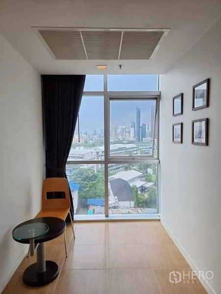 Condominium for rent in Khlong Luang, Pathum Thani - Window nook with chair and side table offering city view near BTS Ekkamai.