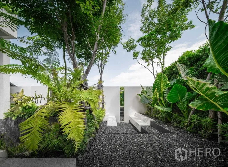 Detached House for sale in Saphan Sung, Bangkok - Landscaped pocket garden with benches, gravel path and tall foliage.