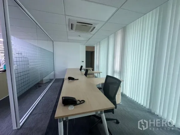 Office Space for rent - Private work area with long bench desks, glass partition and floor-to-ceiling blinds.