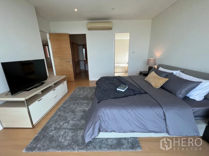 Condominium for rent in Watthana, Bangkok - Master bedroom with TV console, area rug and doorway to bathroom.