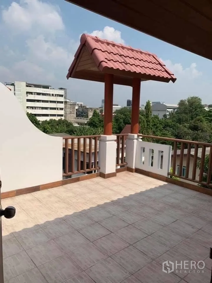 联排别墅 for rent in Watthana, Bangkok - 屋顶露台铺砖，木栏杆，小红瓦顶亭子与城市景观。