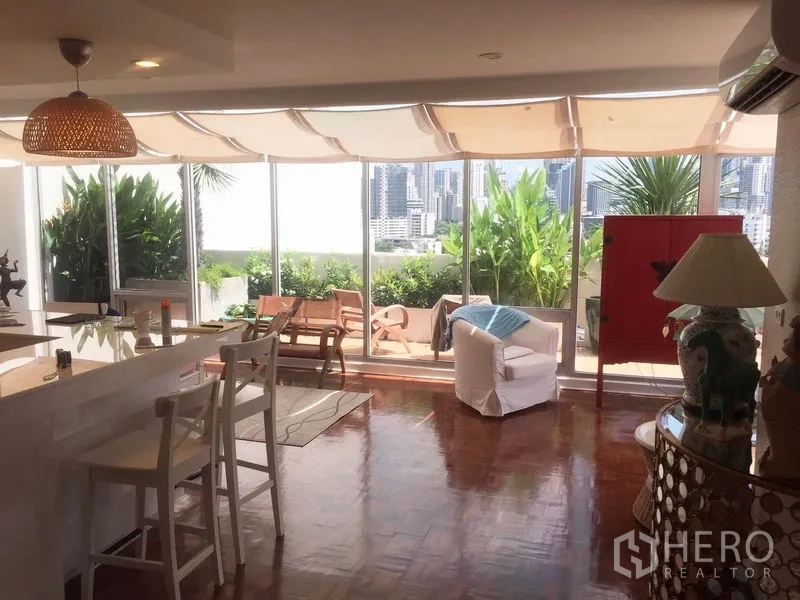 คอนโด ให้เช่าในKhlong Toei, Bangkok - ห้องนั่งเล่นแบบเปิดโล่ง ผนังกระจกเต็มบานเชื่อมสู่เทอเรซสีเขียวพร้อมวิวสกายไลน์กรุงเทพฯ