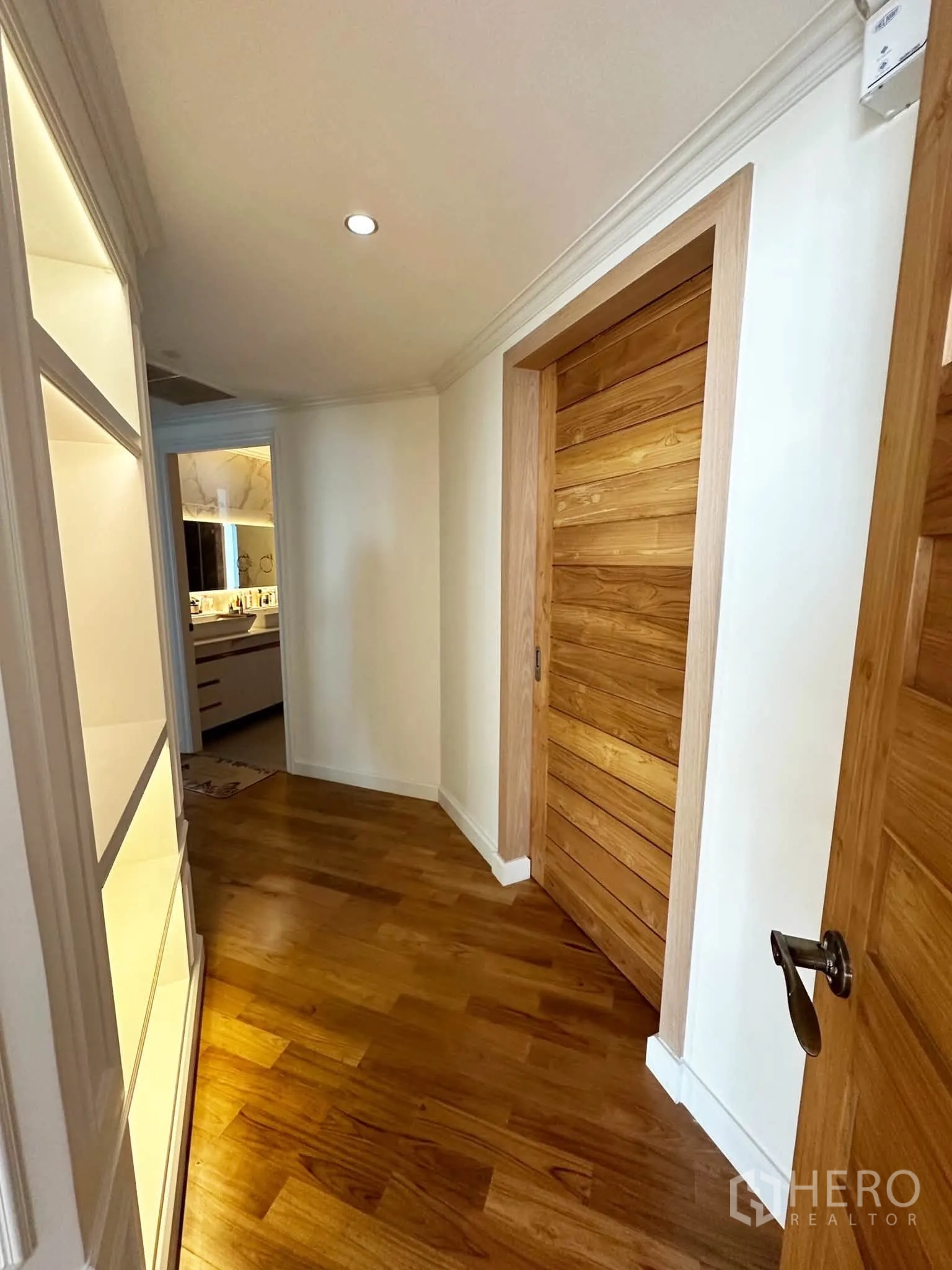 Condominium for sale in Khlong San, Bangkok - Corridor leading toward the bathroom with wooden doors and recessed lighting.