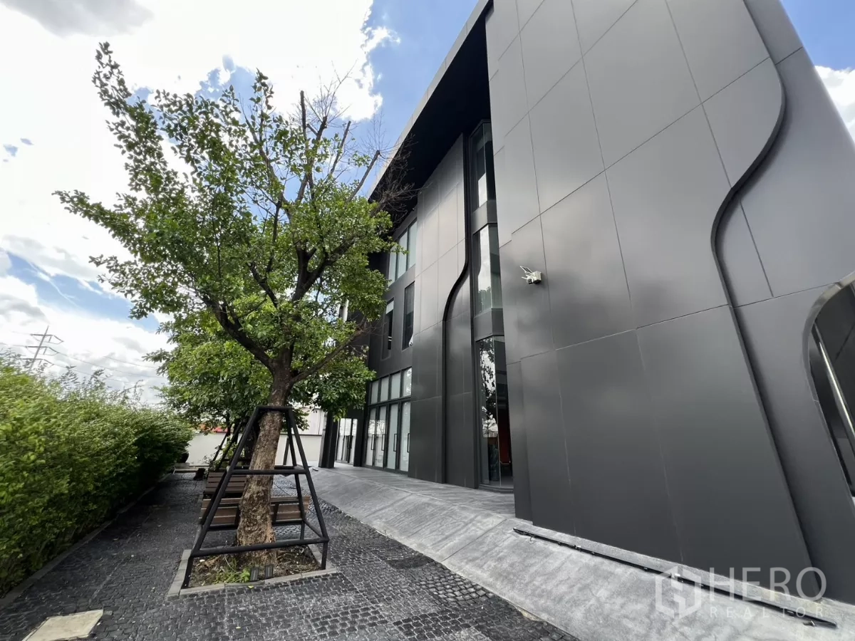 คลังสินค้า ขายในLat Krabang, Bangkok - สวนข้างอาคารมีต้นไม้ คู่กับผนังแผ่นสีดำดีไซน์โมเดิร์น.