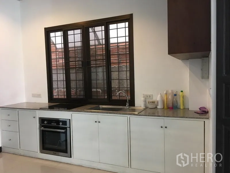 ทาวน์เฮาส์ ให้เช่าในWatthana, Bangkok - ห้องครัวสว่าง เคาน์เตอร์ยาว ตู้สีขาว เตาอบบิวท์อิน และหน้าต่างเหนืออ่าง